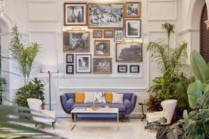 a living room with a blue couch and a wall of pictures at Reid's Palace, A Belmond Hotel, Madeira in Funchal
