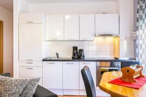 a kitchen with white cabinets and a wooden table at Apartman Nada *** in Medulin