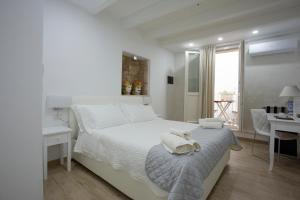 a white bedroom with a bed with towels on it at Vento di Sicilia in Siracusa