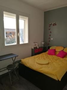 ein Schlafzimmer mit einem großen Bett mit gelber Bettwäsche und rosa Kissen in der Unterkunft Le Moussaillon - F2 à 20 m de la plage in Palavas-les-Flots