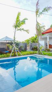 a pool in front of a house with palm trees at Sunburn Villa in Nusa Dua