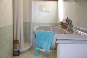 La salle de bains est pourvue d'un lavabo et d'une serviette bleue. dans l'établissement SARDINIA RE - Casa La Spiga, à Castelsardo
