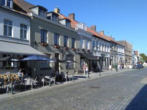 een geplaveide straat met tafels, stoelen en gebouwen bij Gasthof Maerlant in Damme