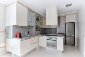 a white kitchen with white cabinets and a refrigerator at Piso recién reformado en el centro de Pamplona in Pamplona