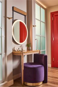 a dressing table with a mirror and a purple chair at Virgin Hotels Dallas in Dallas