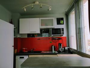 a kitchen with red walls and white cabinets at Le Saint Roch - belle vue mer en plein centre ville in Palavas-les-Flots