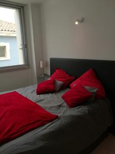 a bed with red pillows on it with a window at Le Saint Roch - belle vue mer en plein centre ville in Palavas-les-Flots