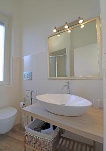ein Badezimmer mit einem Waschbecken, einem WC und einem Spiegel in der Unterkunft Minima in La Maddalena