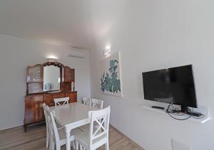 ein Esszimmer mit einem weißen Tisch und einem Flachbild-TV in der Unterkunft Minima in La Maddalena