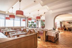 un restaurant avec des tables, des chaises et des fenêtres dans l'établissement Hotel Resort Veronza, à Cavalese