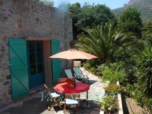 eine Terrasse mit einem Tisch, einem Sonnenschirm und Stühlen in der Unterkunft Villa Sorbo in LʼÎle-Rousse