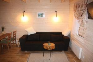 a living room with a black couch and a table at Chaty Mazur w Wierzbie in Ruciane-Nida +12 photos