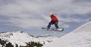 een man die door de lucht vliegt terwijl hij op een snowboard rijdt bij Hunter's Lodge in Neve Ativ