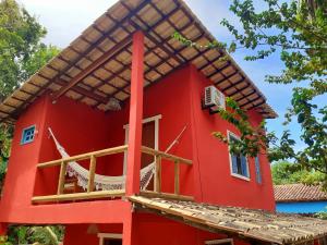 uma casa vermelha com uma varanda em Trancoso, Bahia - Casa por temporada com estacionamento em Trancoso