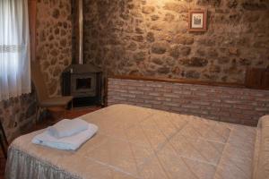 1 dormitorio con cama y pared de ladrillo en Casa Rural La Pastera, en Trevejo