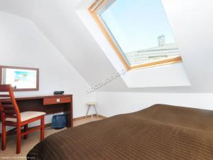 a bedroom with a bed and a desk and a window at Pod Muzami in Rewal