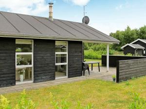 una casa negra con una mesa de picnic delante de ella en 6 person holiday home in Hals en Hals