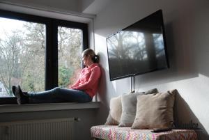 een vrouw die op een vensterbank zit te praten op een mobiele telefoon bij 500 Miles Apartments in Bonn