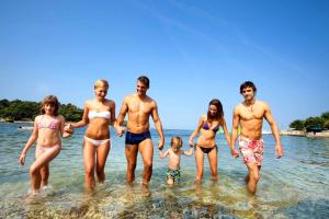 a group of people standing in the water at the beach at Hotel Istra Plava Laguna in Poreč