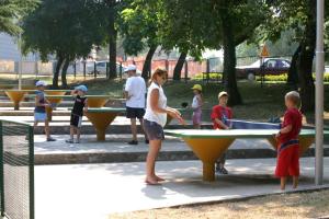 a woman playing ping pong in a park with children at Hotel Istra Plava Laguna in Poreč