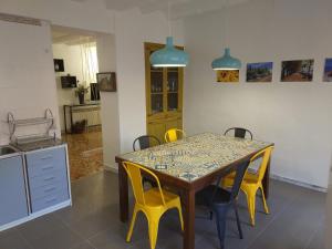 a dining room table with yellow chairs and a kitchen at Casa Mineta in Cretas