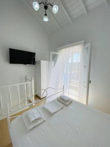a white bedroom with a bed with two towels on it at Pontamos Villas in Halki