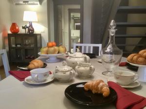 a table with tea cups and croissants on it at Guinigi Luxury Loft Historical Center of Lucca in Lucca