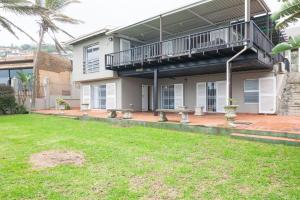 a house with a deck and a grass yard at Comp Beach Road 25 - FAMILY ONLY in Ballito