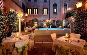 un ristorante con tavoli bianchi e una piscina di Hotel Giorgione a Venezia