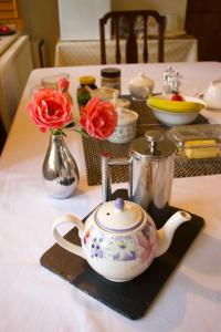 einen Tisch mit einer Teekanne und Blumen darauf in der Unterkunft Bagnell Farm Cottage in Chiselborough