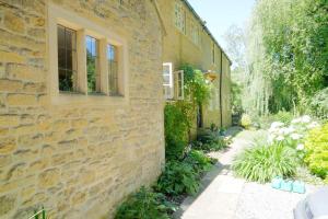 a stone house with a garden next to a building at Bagnell Farm Cottage in Chiselborough