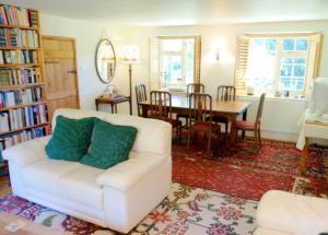 a living room with a white couch and a dining room at Bagnell Farm Cottage in Chiselborough