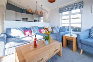 a living room with a blue couch and a table at Sea Breeze - Aldeburgh Coastal Cottages in Sizewell
