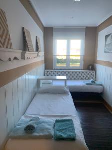 mały pokój z 2 łóżkami i oknem w obiekcie apartamento con jardín privado y barbacoa a 5 min playas santander w mieście Santander