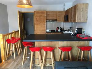une cuisine avec comptoir et tabourets de bar rouge dans l'établissement appart chalet hameau des rennes - luxe -pied des pistes, à Vars
