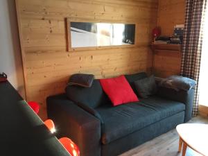 - un salon avec un canapé vert et un oreiller rouge dans l'établissement appart chalet hameau des rennes - luxe -pied des pistes, à Vars
