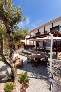 un patio con mesa, sillas y sombrilla en Ayia Marina Suites, en Ouranoupoli