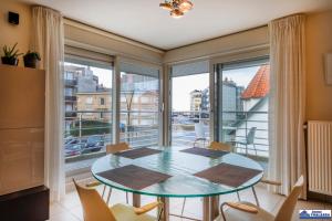 a dining room with a table and chairs and a large window at Amena 0101 + garage in Koksijde