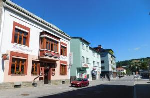 um carro vermelho está estacionado numa rua ao lado de edifícios em HOTEL BRITANNIA VSETÍN em Vsetín