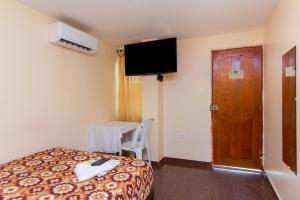 Habitación de hotel con cama, mesa y TV en Hotel Boquilla Suites By GEH Suites, en Cartagena de Indias