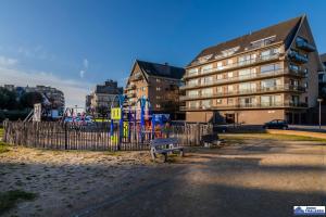 a park with two benches in front of a building at Zandstuyver 0503 in Koksijde