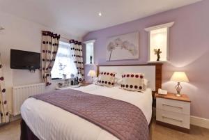 a bedroom with a large bed with purple walls at Lauriston & Lawton Court Hotel in Llandudno