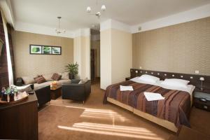Habitación de hotel con cama y sofá en Hotel & SPA Odeon, en Boguchwała