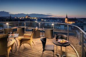 a balcony with tables and chairs and a view of a city at Design Metropol Hotel Prague in Prague