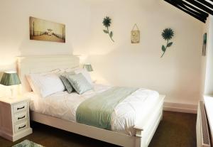 a bedroom with a white bed with a nightstand and a bed sidx sidx sidx at Beautiful Beach Front Cottage in Llandudno
