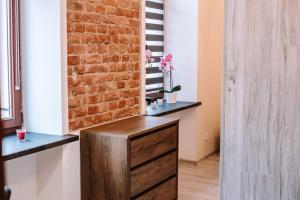 a room with a brick wall and a wooden dresser at Voal Rezydencja in Lublin