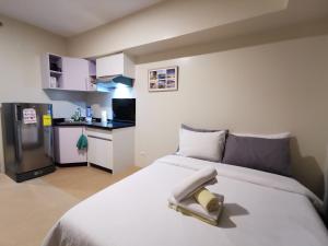a bedroom with a white bed and a small kitchen at Avida Davao by davaobnb & Lemonique Homes in Davao City