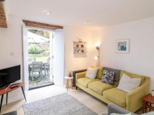 sala de estar con sofá amarillo y TV en 1 Jubilee Cottage, en Tintagel