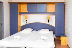 two beds in a room with a blue headboard at SOWELL RESIDENCES Chênes Verts in Saint-Raphaël