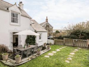 un jardín con mesa y sombrilla en 1 Jubilee Cottage, en Tintagel
